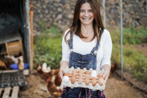 Locan business woman holding the rewards of her work - the eggs from her chickens! Business loans - Coastal Finance - Finance Broker - Melbourne & Tasmania
