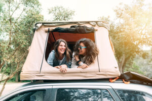 Young people camping in new tent on top of car. Freedom of choice through financing. Coastal Finance - Finance Broker - Melbourne and Tasmania